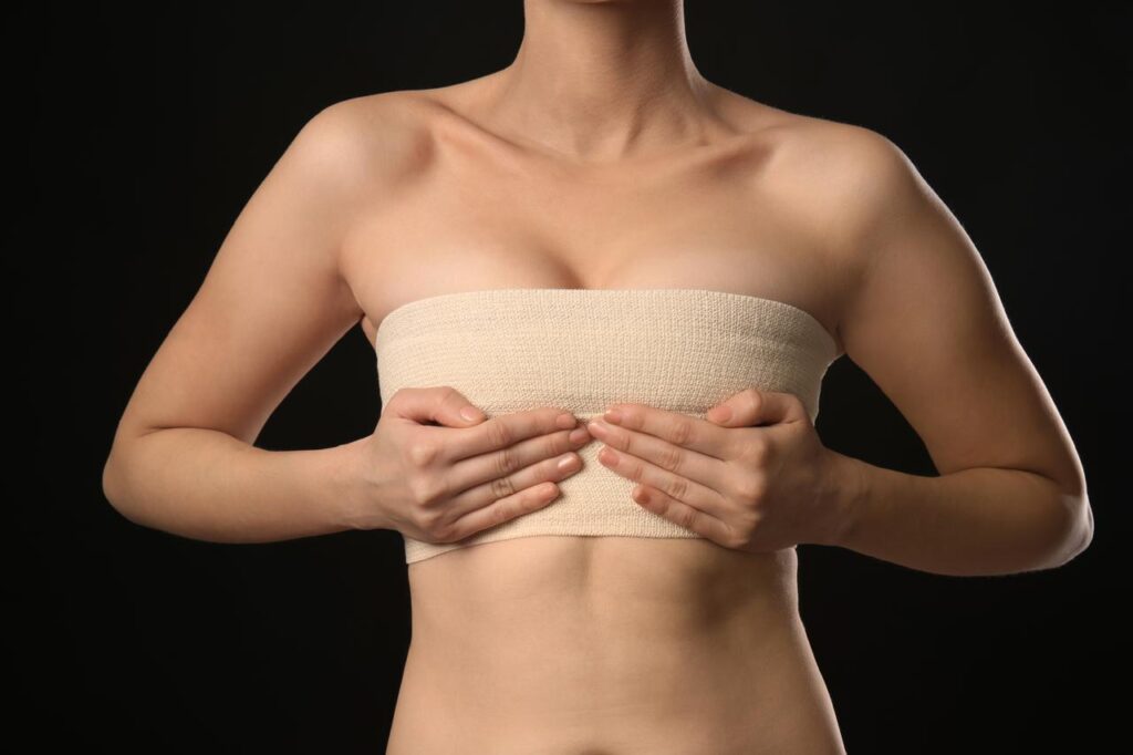 Mujer tocando su pecho en periodo posquirúrgico de mamoplastia de aumento
